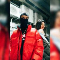 man wearing mask and red jacket standing beside woman