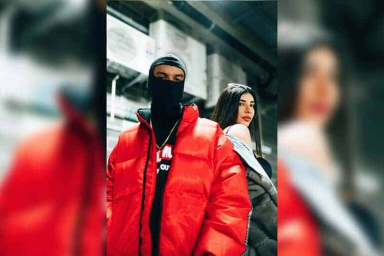 hombre con máscara y chaqueta roja de pie junto a una mujer