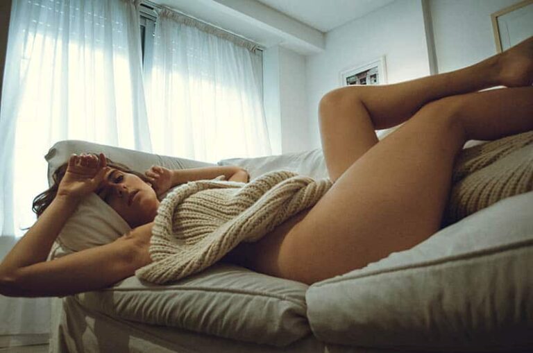 naked woman covered with blanket lying on couch