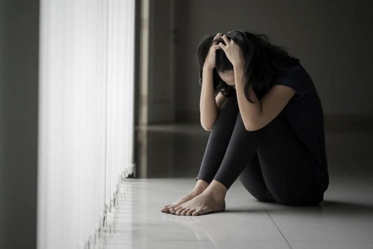 mujer deprimida sentada en el suelo