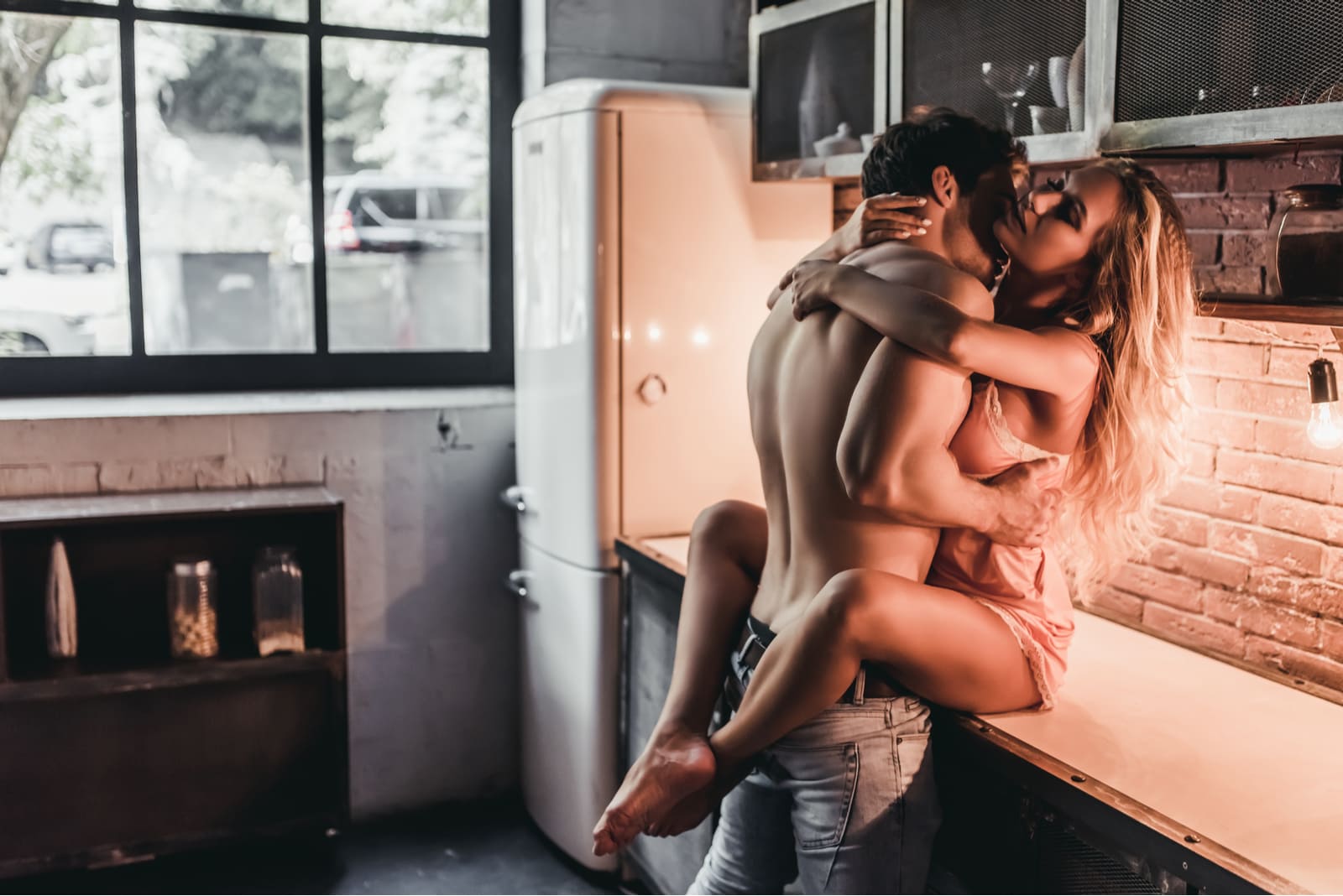the man put the woman in the kitchen and kissed her