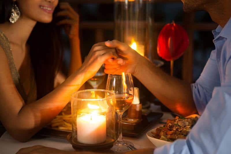 close up photo of couple having date dinner and holding hands