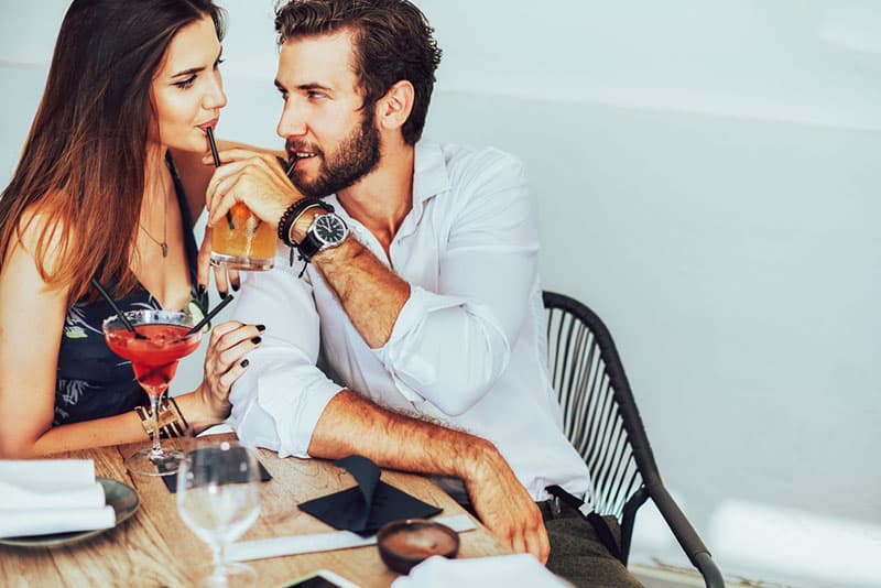 casal a namoriscar e a beber uma bebida juntos