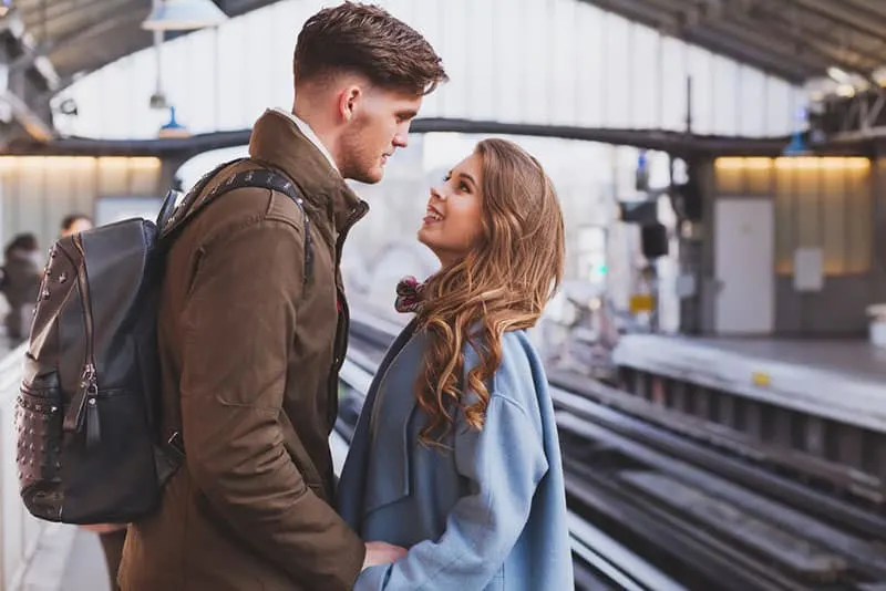 couple holding their hand and looking each other at train station