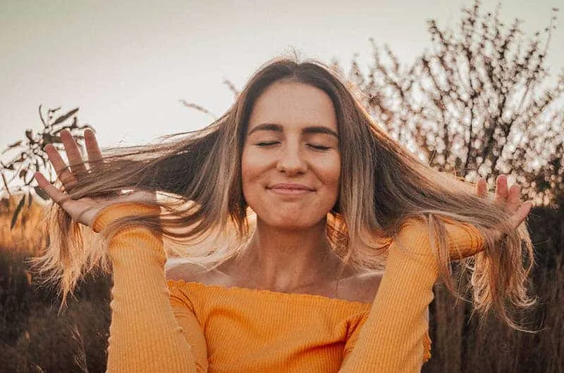 happy blonde woman touching her hair