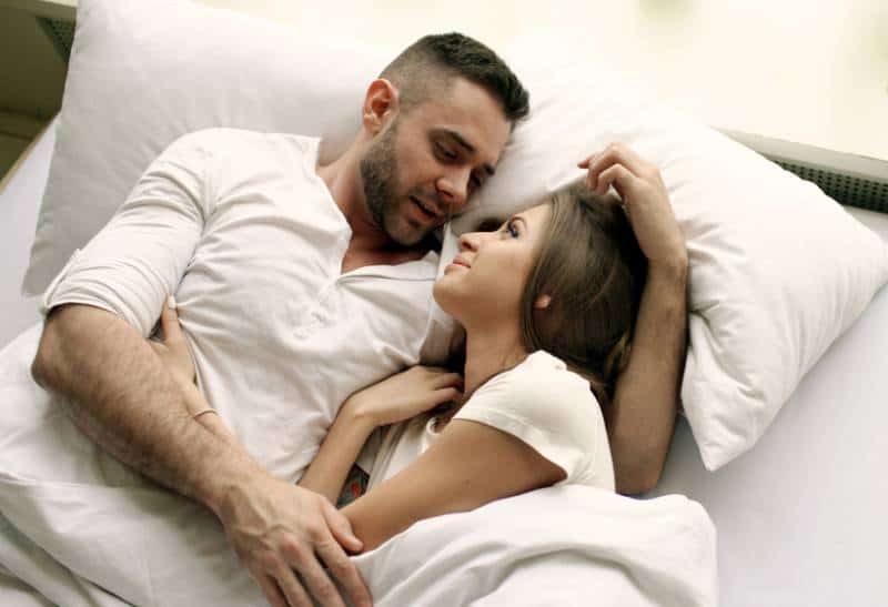 Una coppia di innamorati parla e si abbraccia a letto