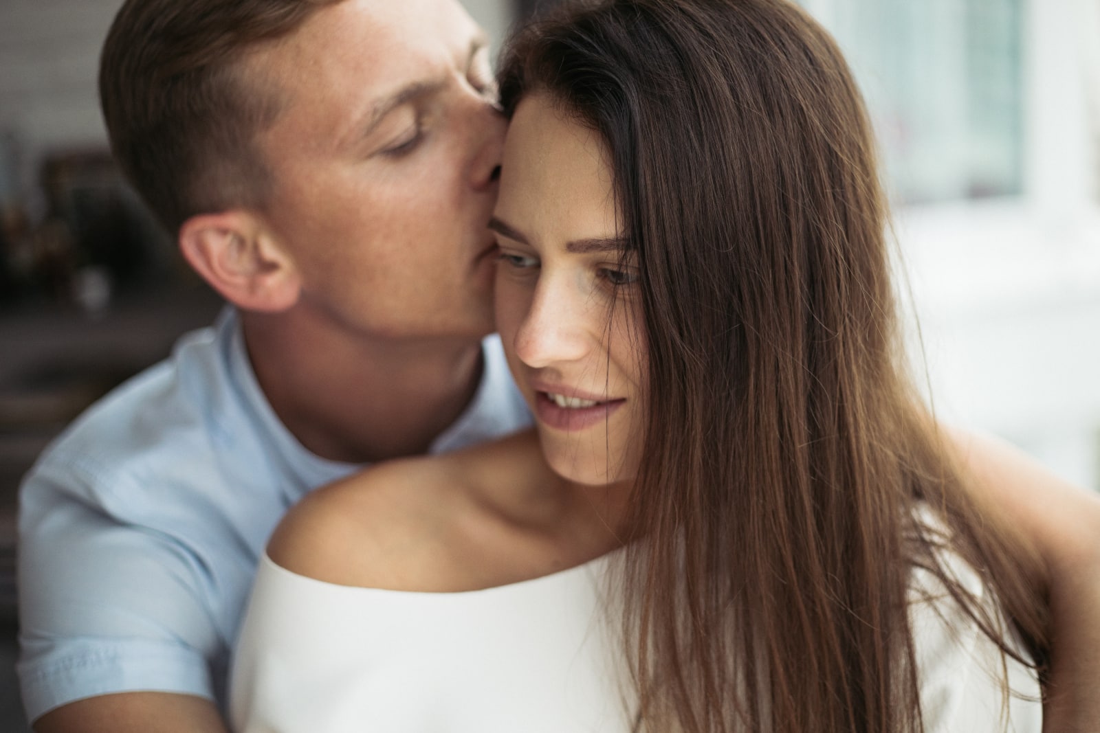 man kissing woman in forehead