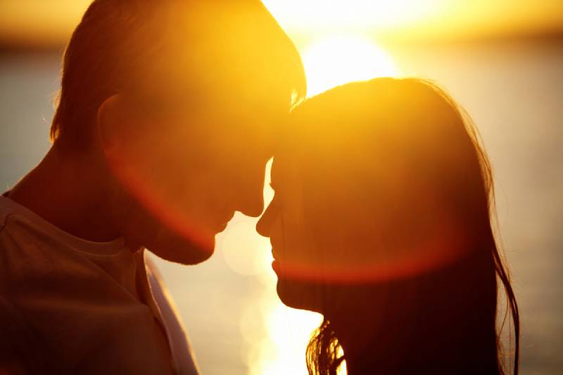 romantic couple looking each other on background of sunset