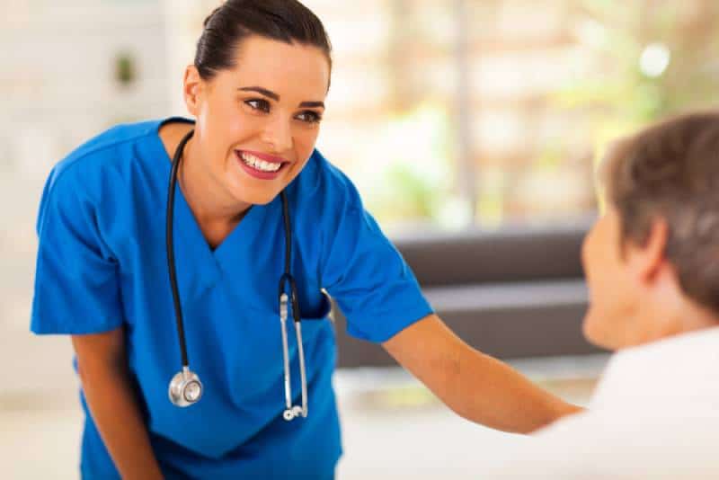 joven enfermera sonriente hablando con una mujer madura