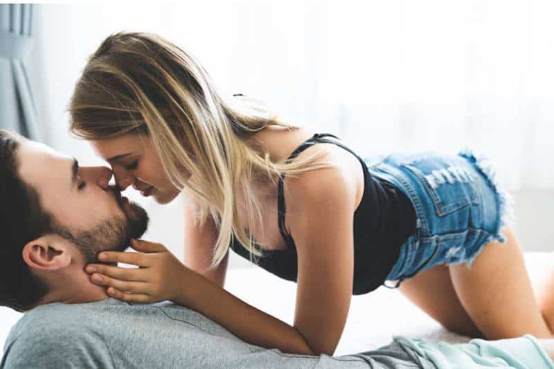 woman going on man while he is lying on bed