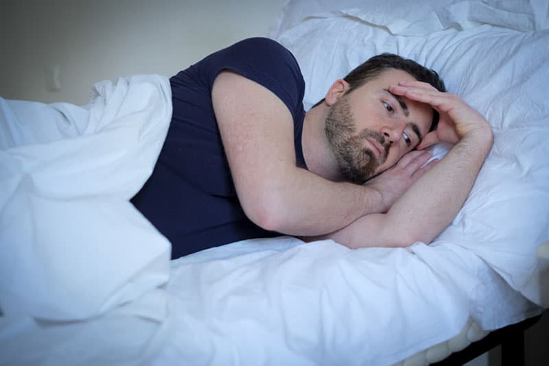 worried man laying in bed