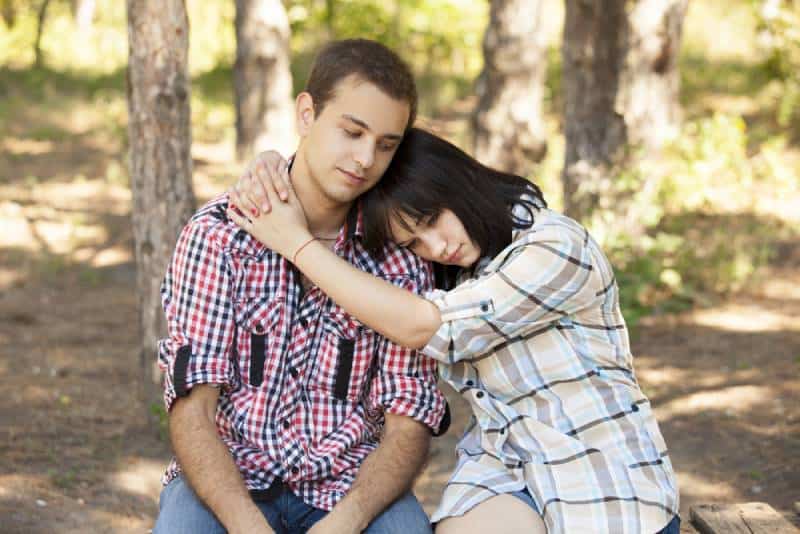 young sad teenage couple in a green park.