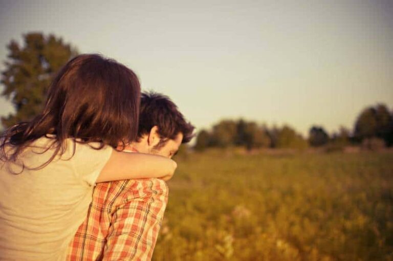 man carrying woman walking on grass field