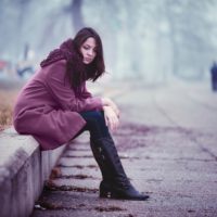young sad woman sitting outside alone