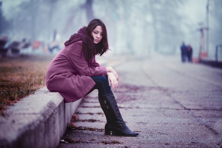 young sad woman sitting outside alone