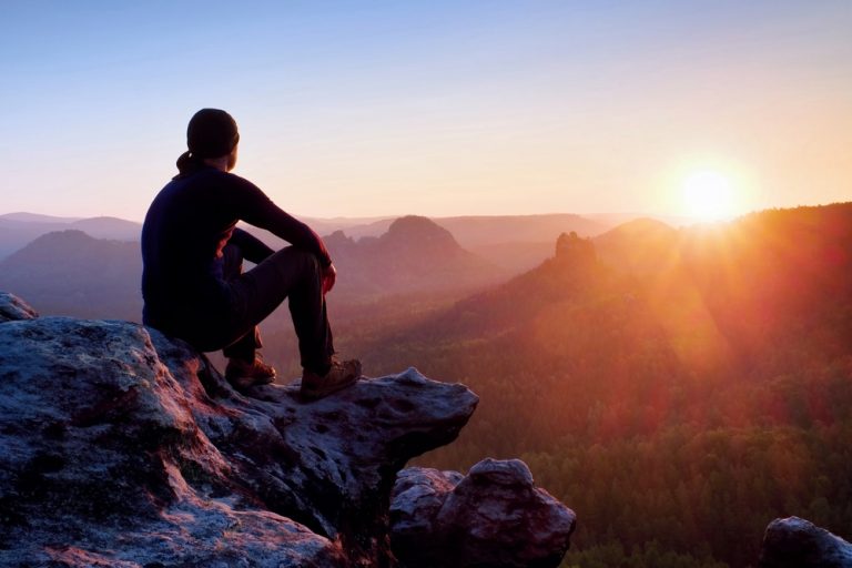 a man sitting on a rock with his back turned