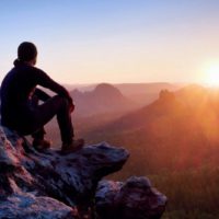 a man sitting on a rock with his back turned