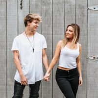 man and woman in white shirt and black jeans holding their hands outside