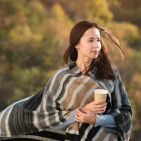 thoughtful woman holding cup of tea outside