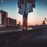 mujer con botas y chaqueta caminando al aire libre