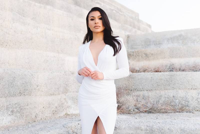 woman wearing white dress and standing beside wall