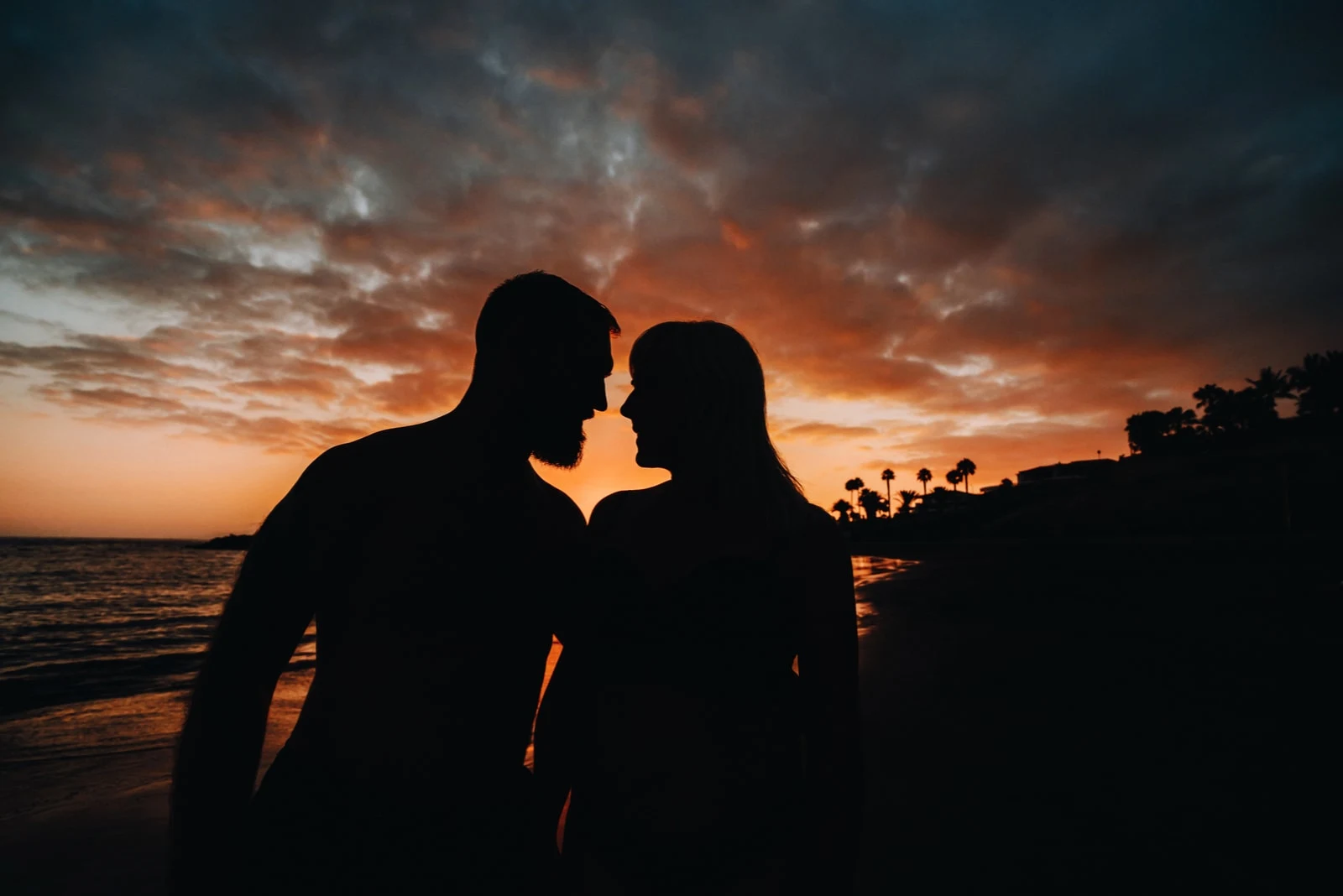 Romantic couple on the beach in a colorful sunset in the background