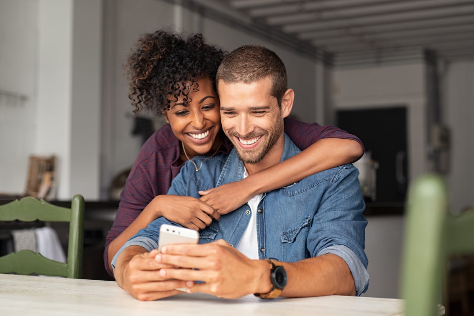 Giovane coppia sorridente abbracciata mentre guarda lo smartphone