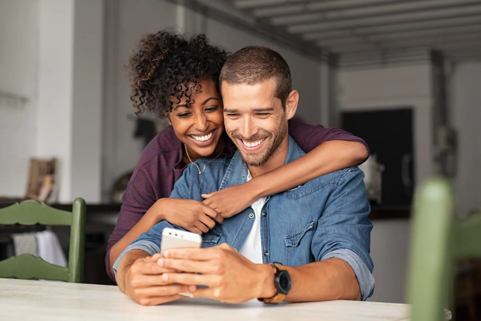 Smiling young couple embracing while looking at smartphone