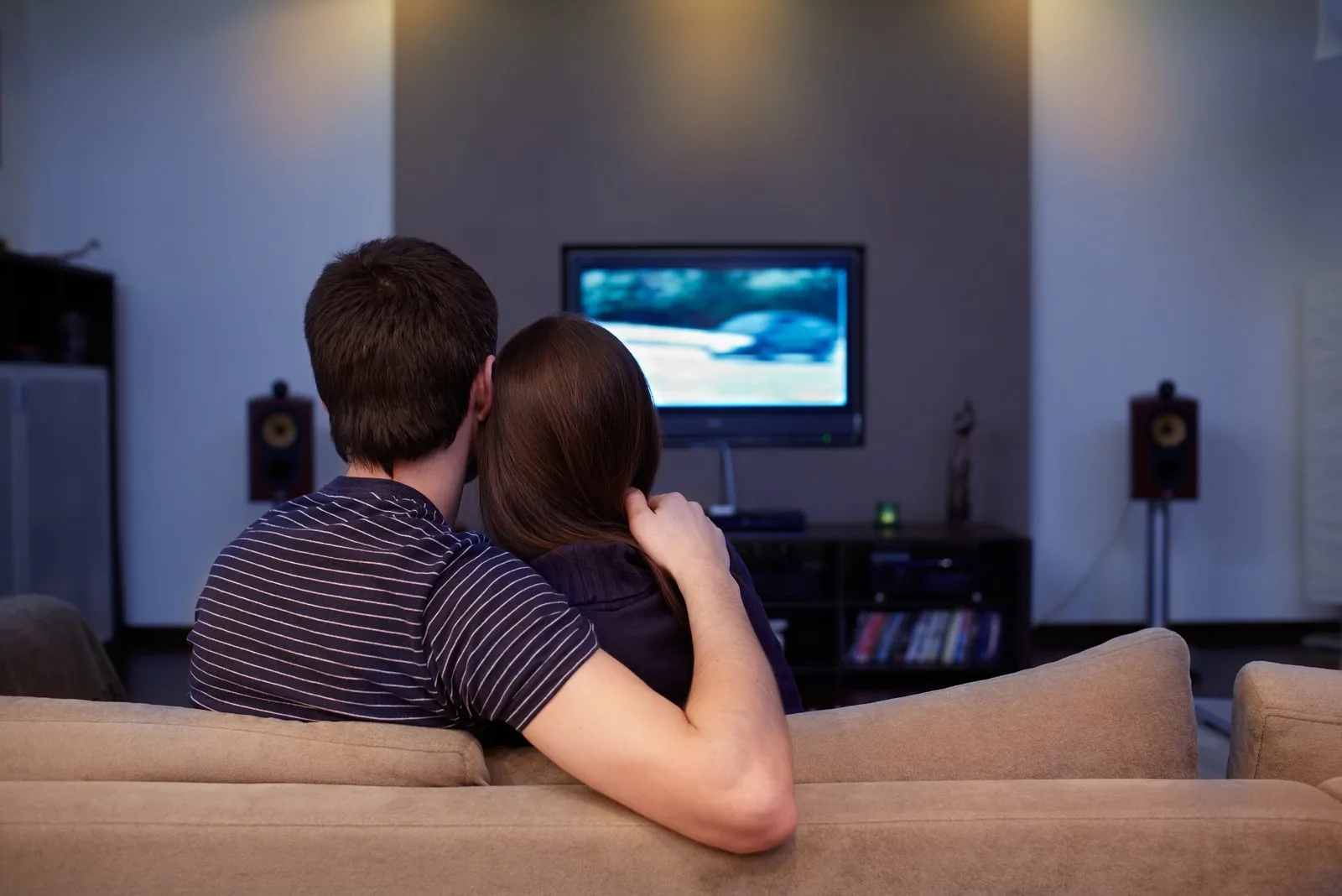 a man and a woman watching tv hugged