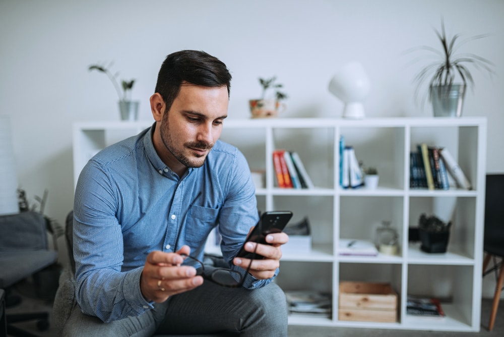 un uomo siede e digita al telefono