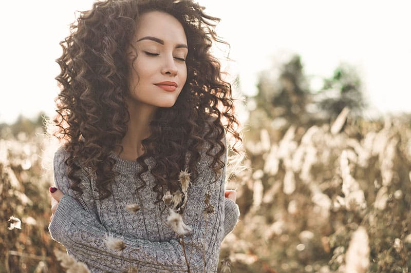 utiful woman standing in the field with closed eyes