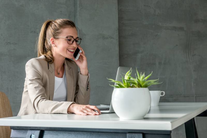 mujer de negocios atendiendo una llamada sentada en su escritorio