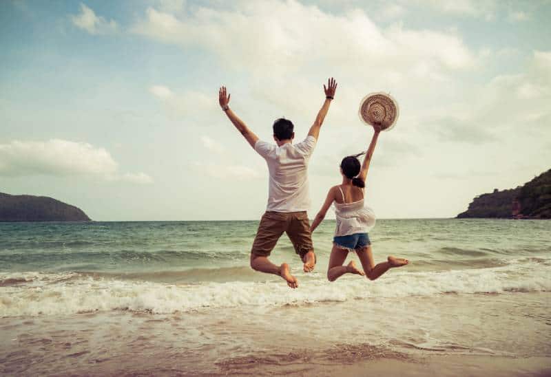 pareja saltando en la arena de la playa