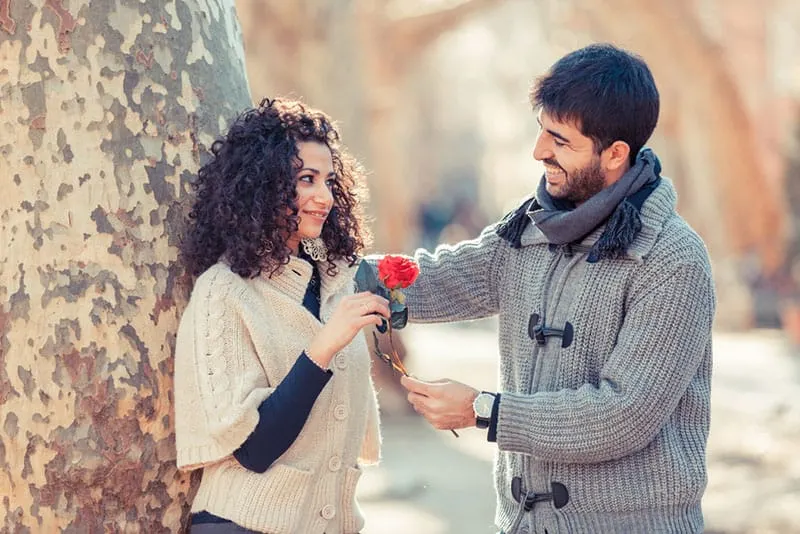 happy man giving a flower to woman