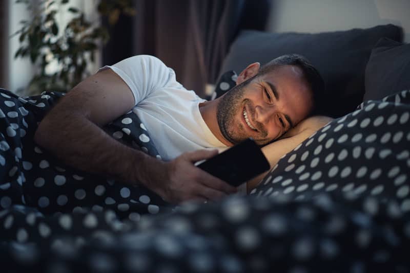 happy man typing on his phone during night