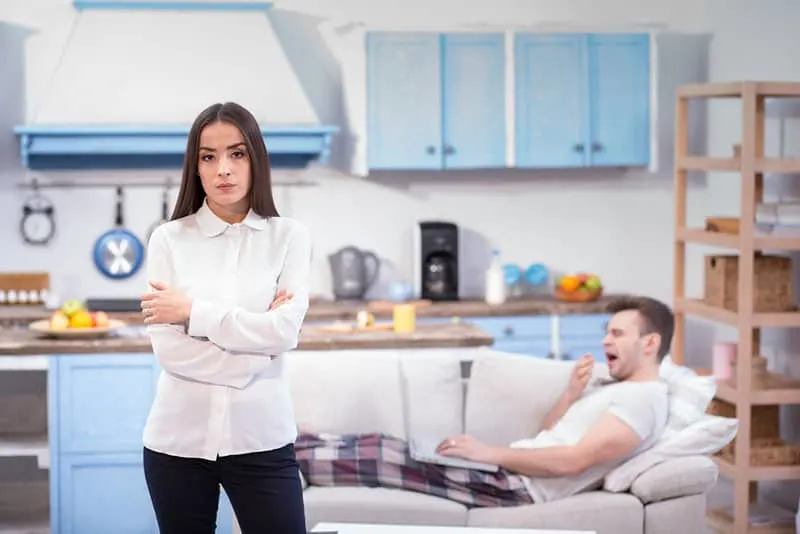 lazy man laying on sofa while woman standing angry