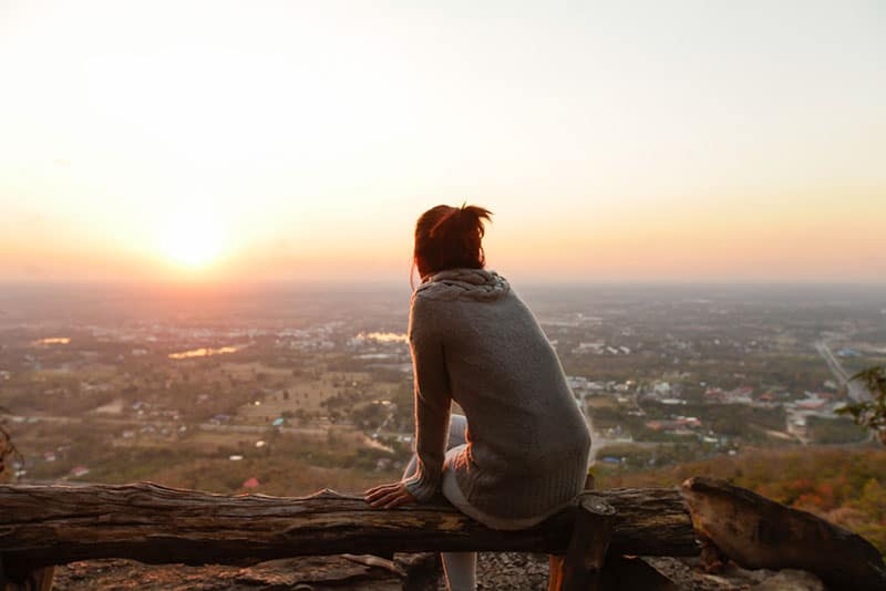 mujer solitaria mirando la puesta de sol