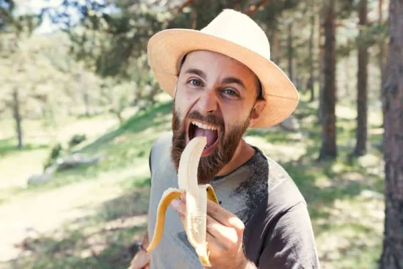 man eating a banana in nature