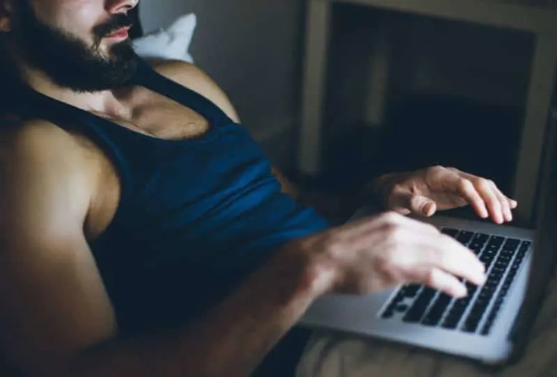 man typing on his laptop before sleep