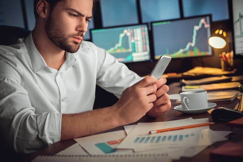 uomo pensieroso che guarda il telefono