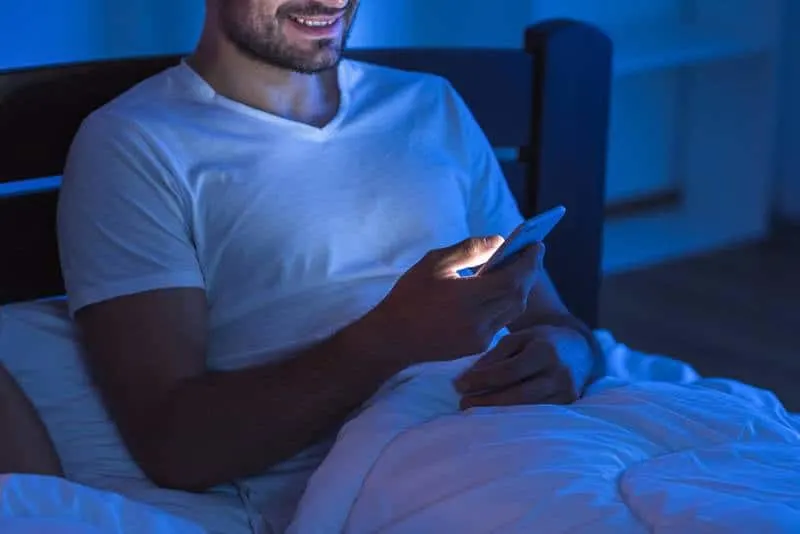smiling man typing on his phone during night
