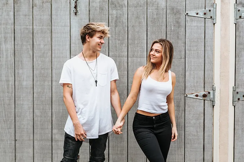 smiling young beautiful couple standing in front of wooden fence