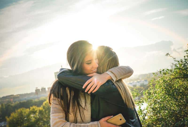 two friends hugging at sunset outdoor