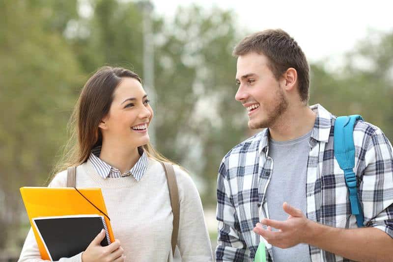 two smiling college students talking outside