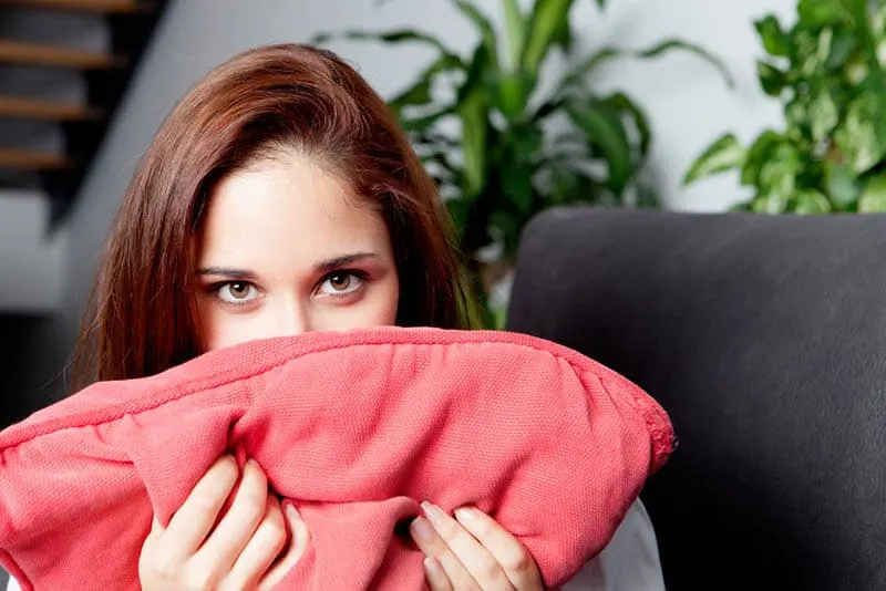 woman covered her mouth with pillow