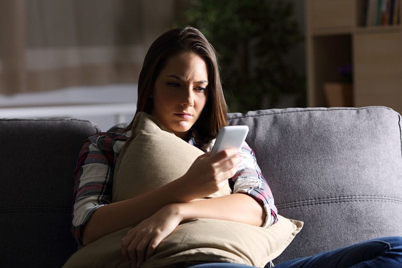 woman sitting on the couch with phone in hands
