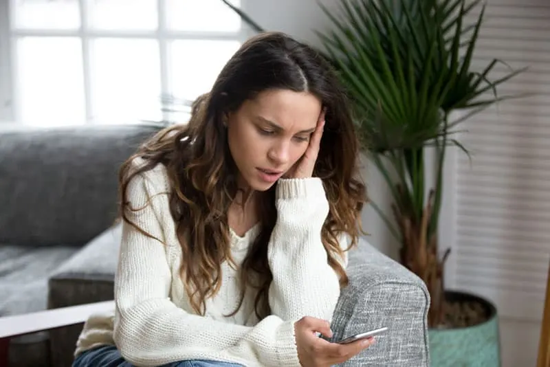 worried woman reading message on smartphone