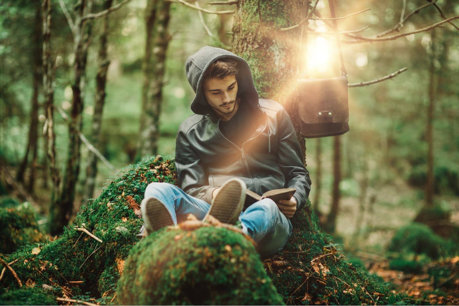 young man reading book while sitting in nature