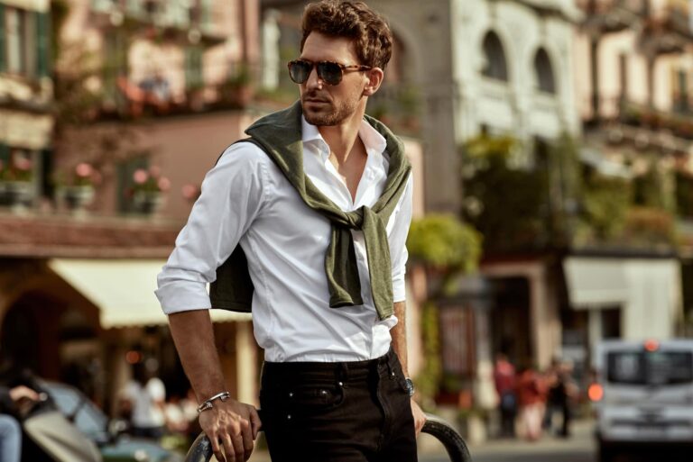 man wearing sunglasses and white shirt with tied sweater on shoulders