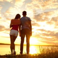 pareja romántica de pie y mirando la puesta de sol